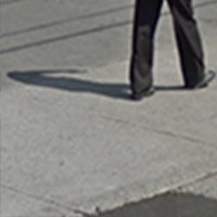 A pair of legs walking away on the sidewalk, created by Lillian Ross-Millard.